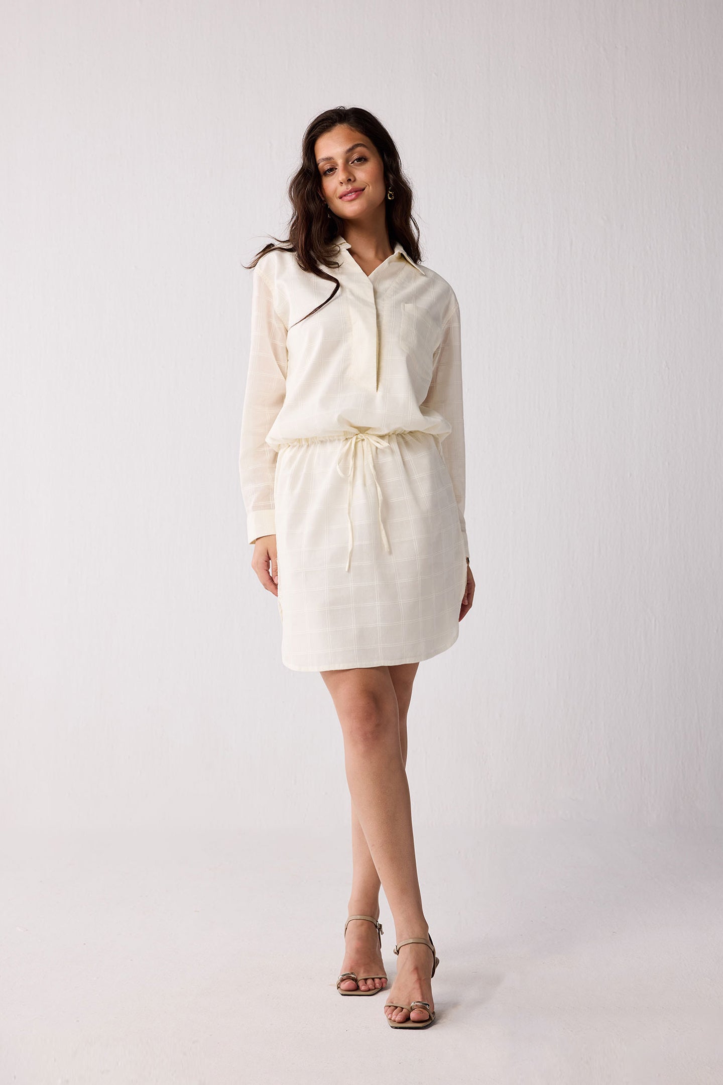 A woman wearing a white outfit against a plain background