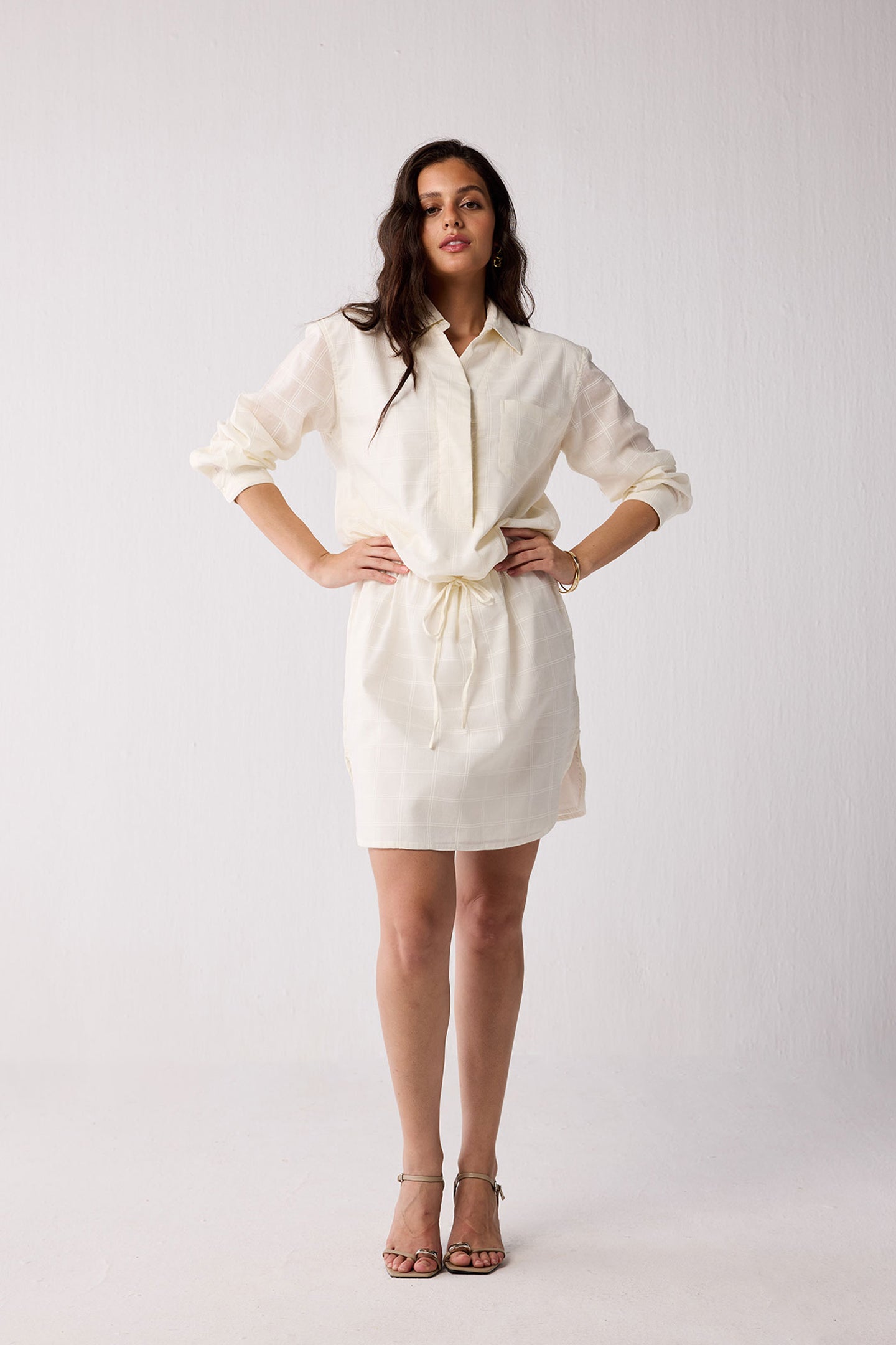 A woman wearing a white dress on a plain background