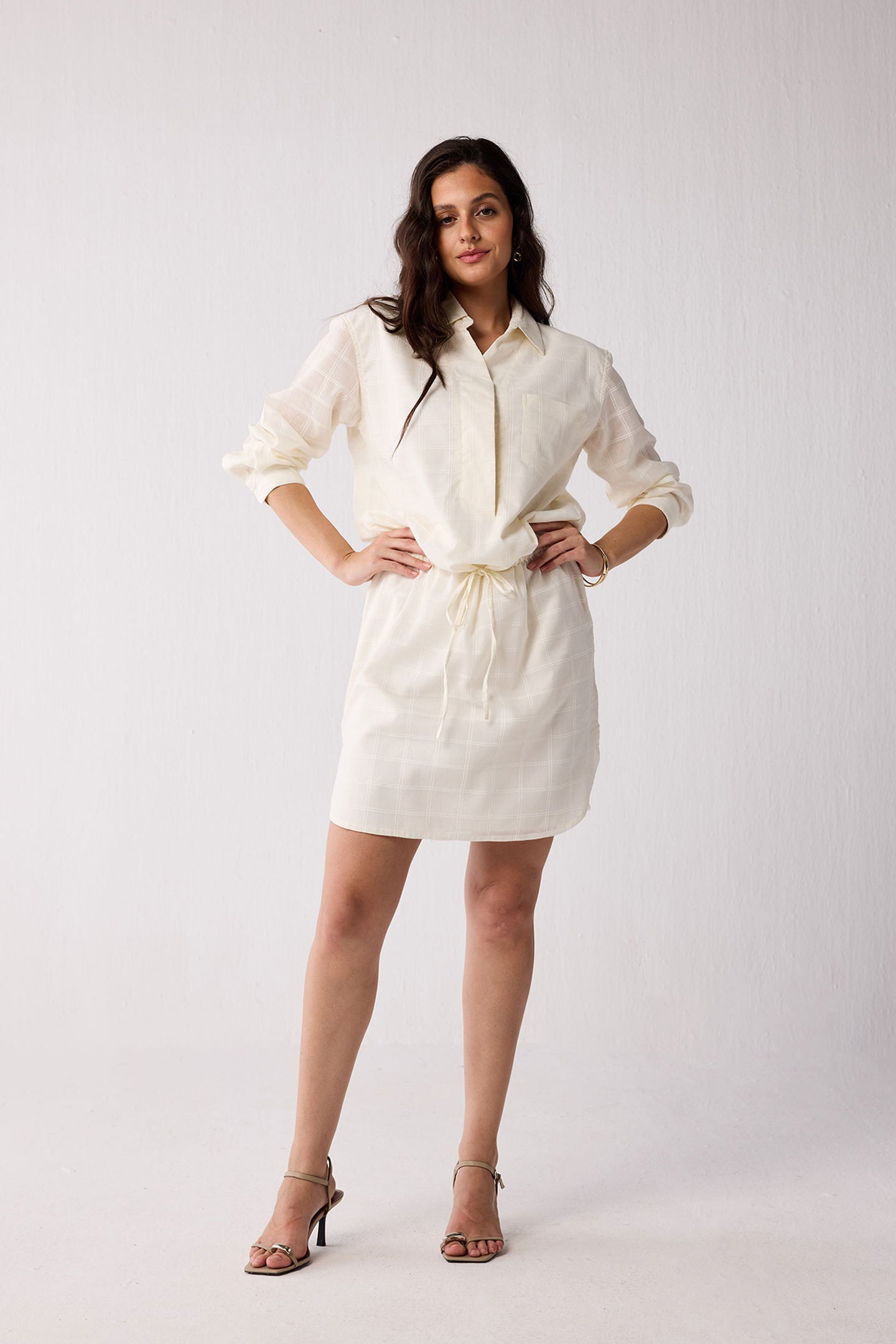 A woman wearing a white dress on a plain background