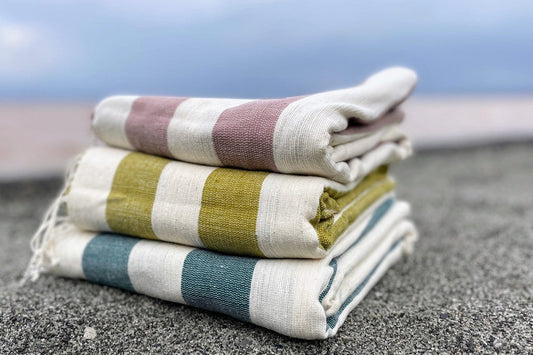 Omo beach towel in clay, moss, teal on sand 