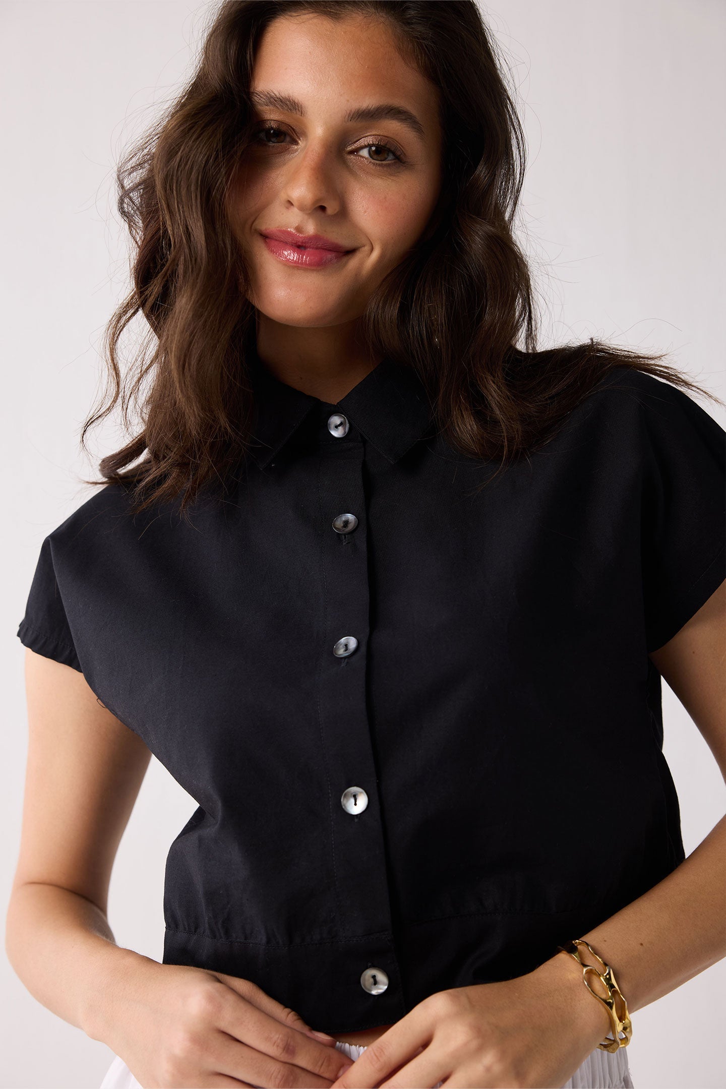 Woman wearing a black top and white skirt against a plain background