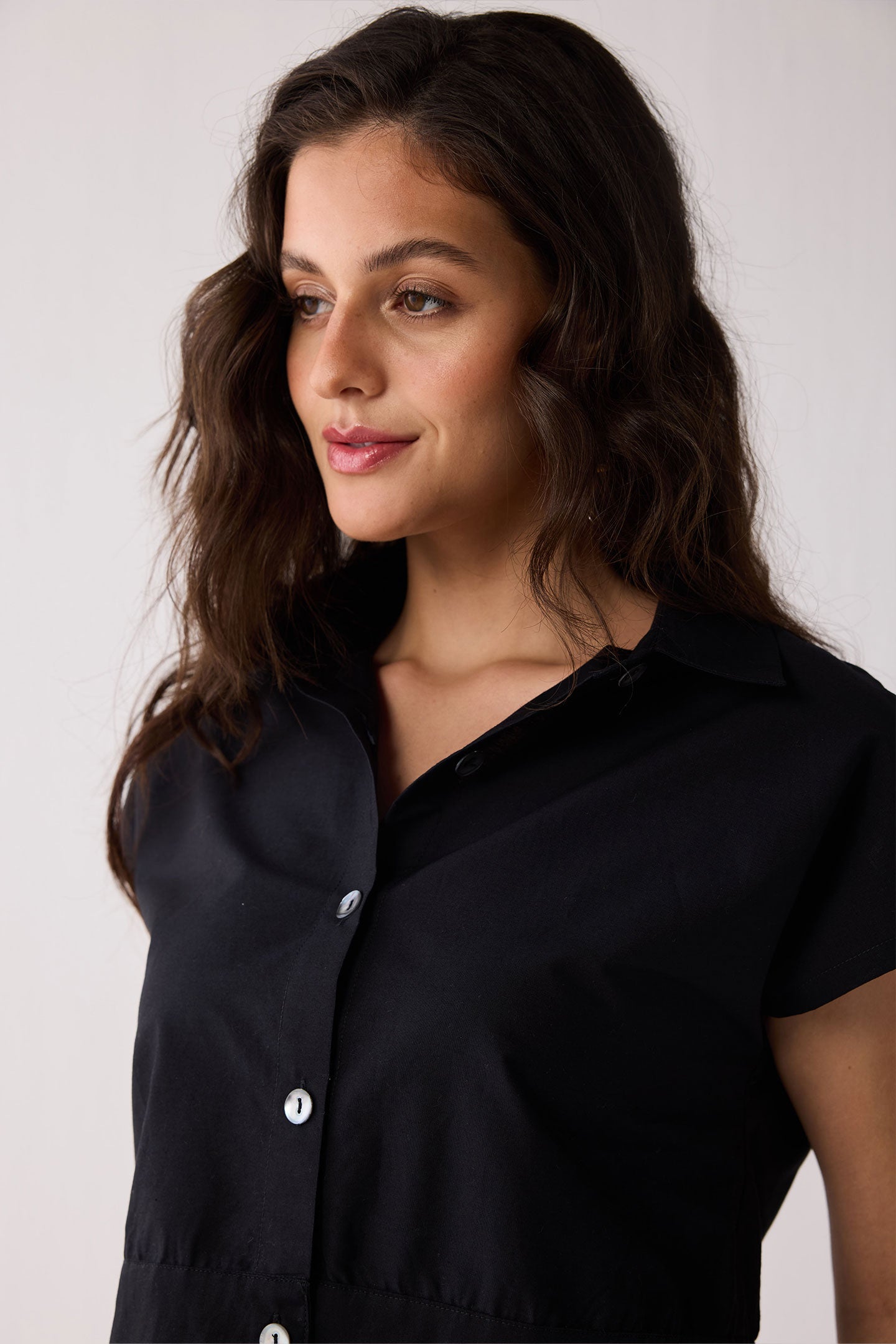 Woman wearing a black top and white skirt against a plain background