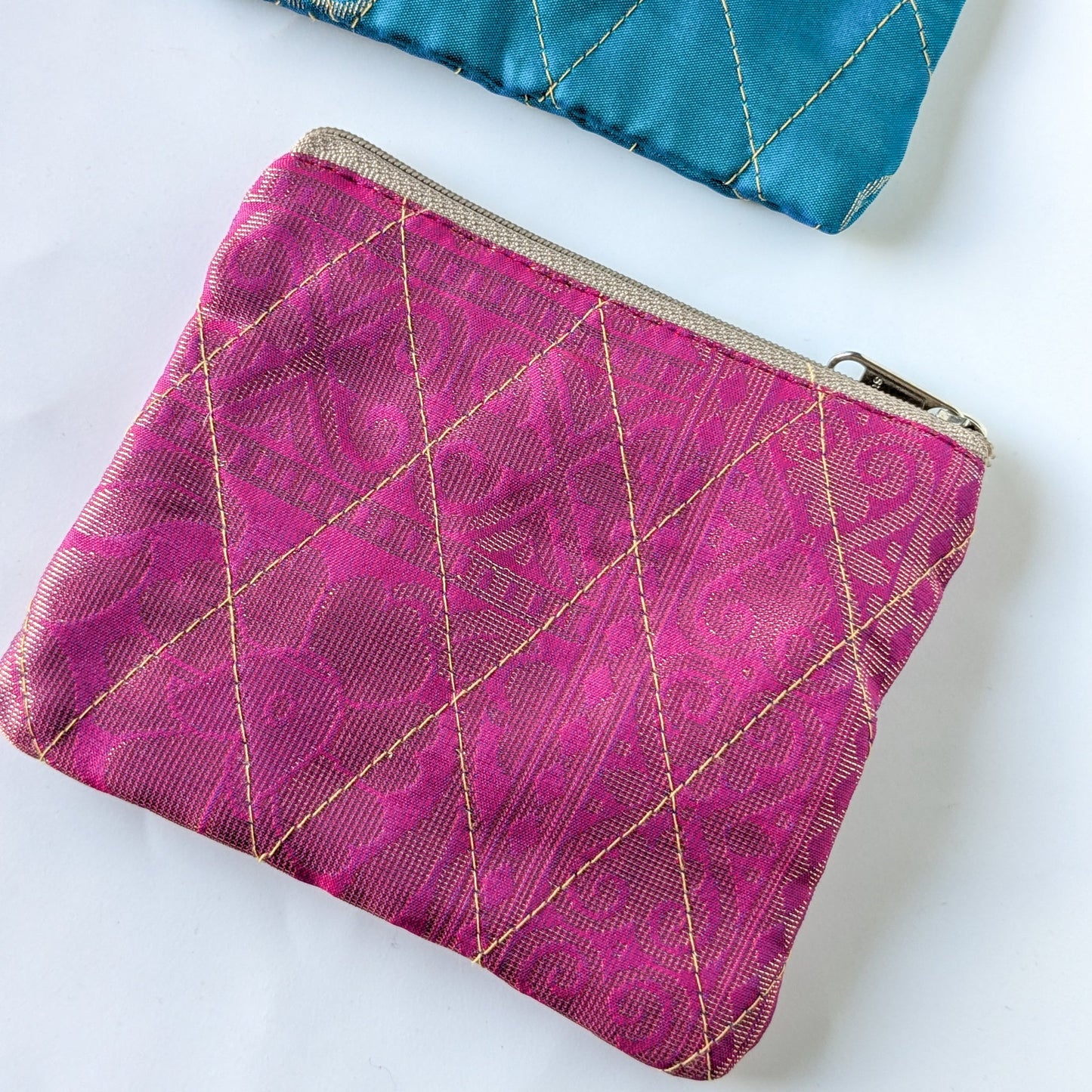 Pink fabric pouch with gold stitching on a white background