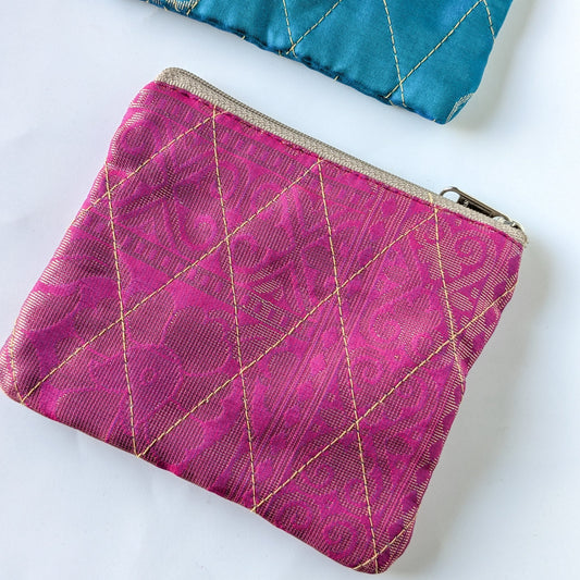 Pink fabric pouch with gold stitching on a white background