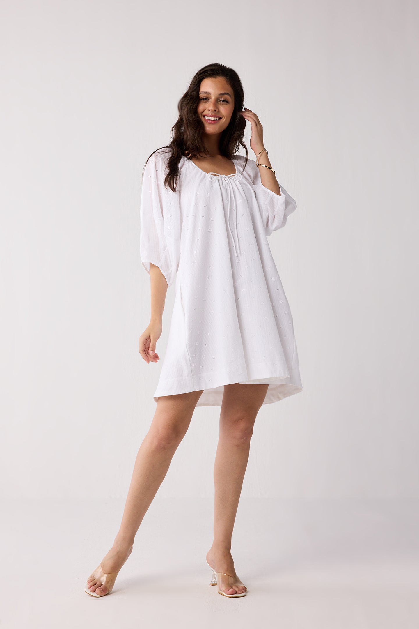 A woman wearing a white dress on a plain background.