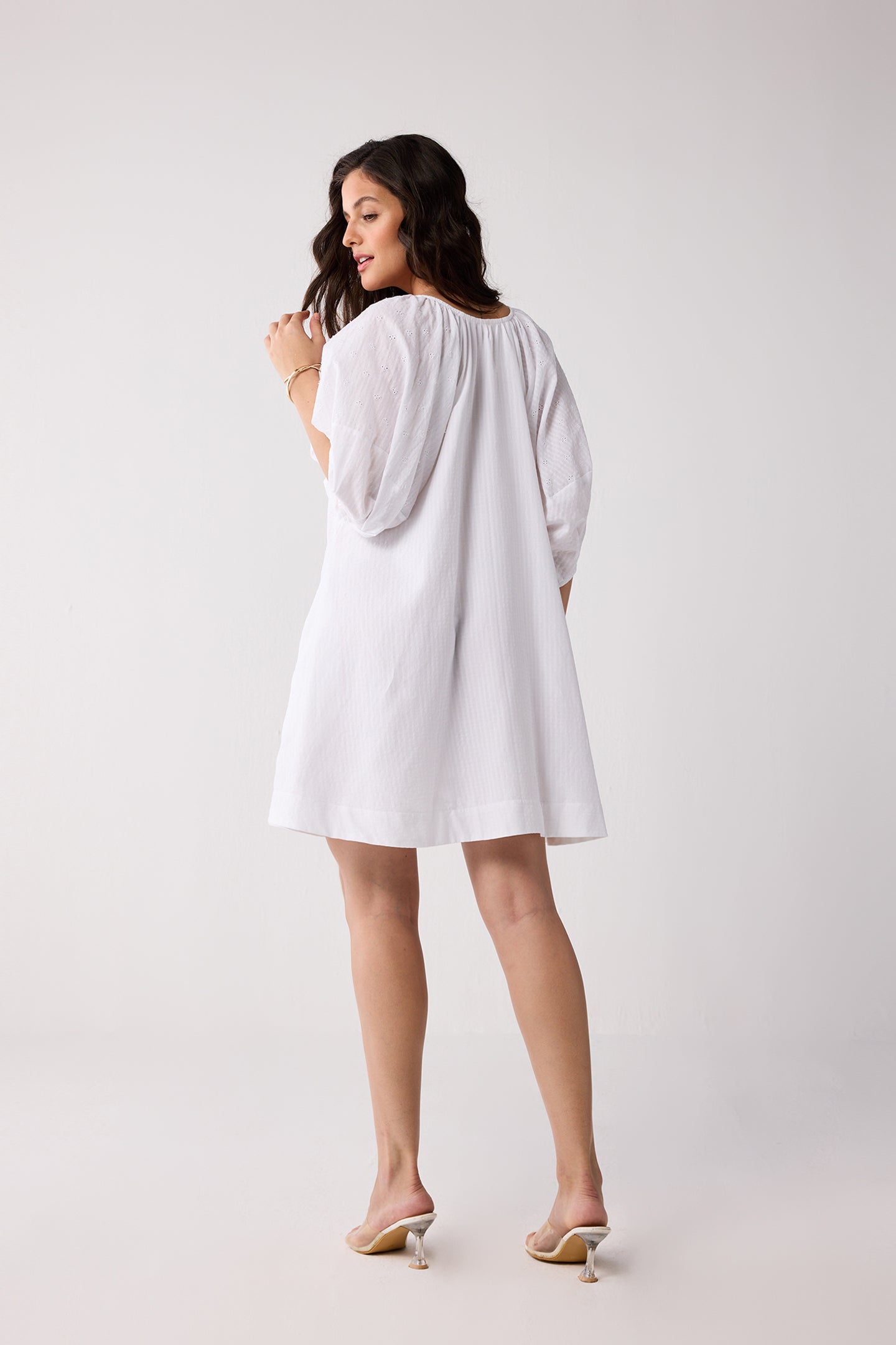 A woman wearing a white dress on a plain background.