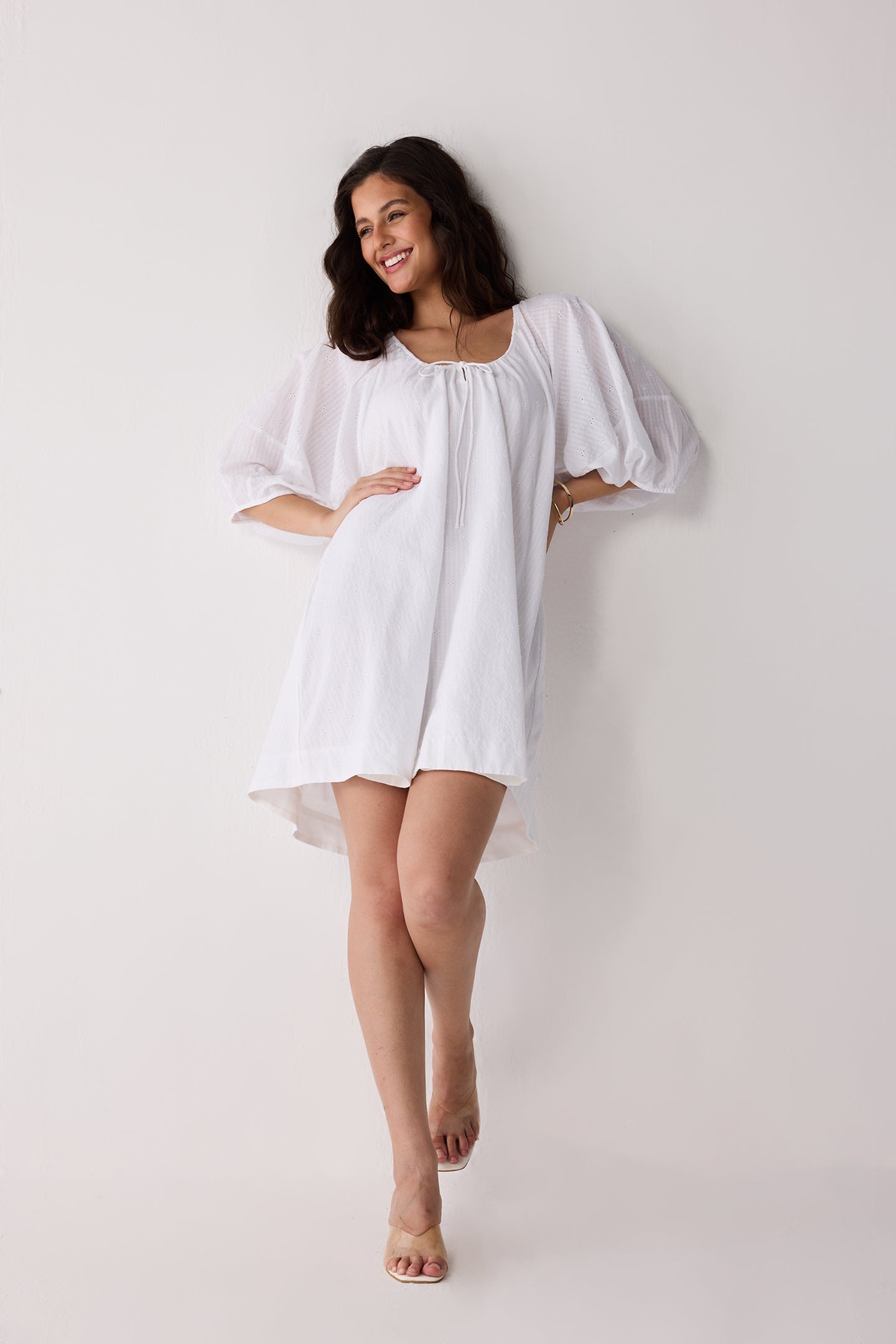 A woman wearing a white dress on a plain background.