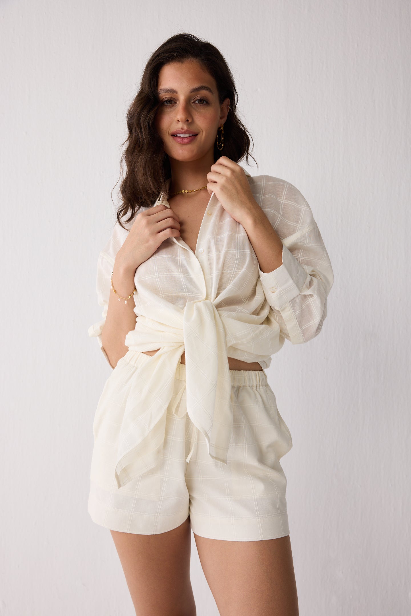 A woman wearing a white outfit against a plain background
