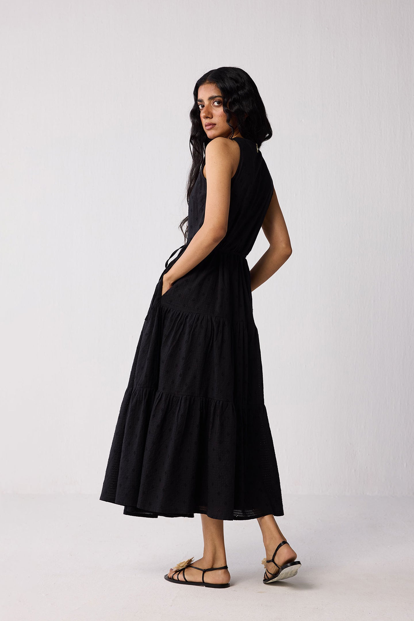 Woman wearing a black sleeveless dress against a white background
