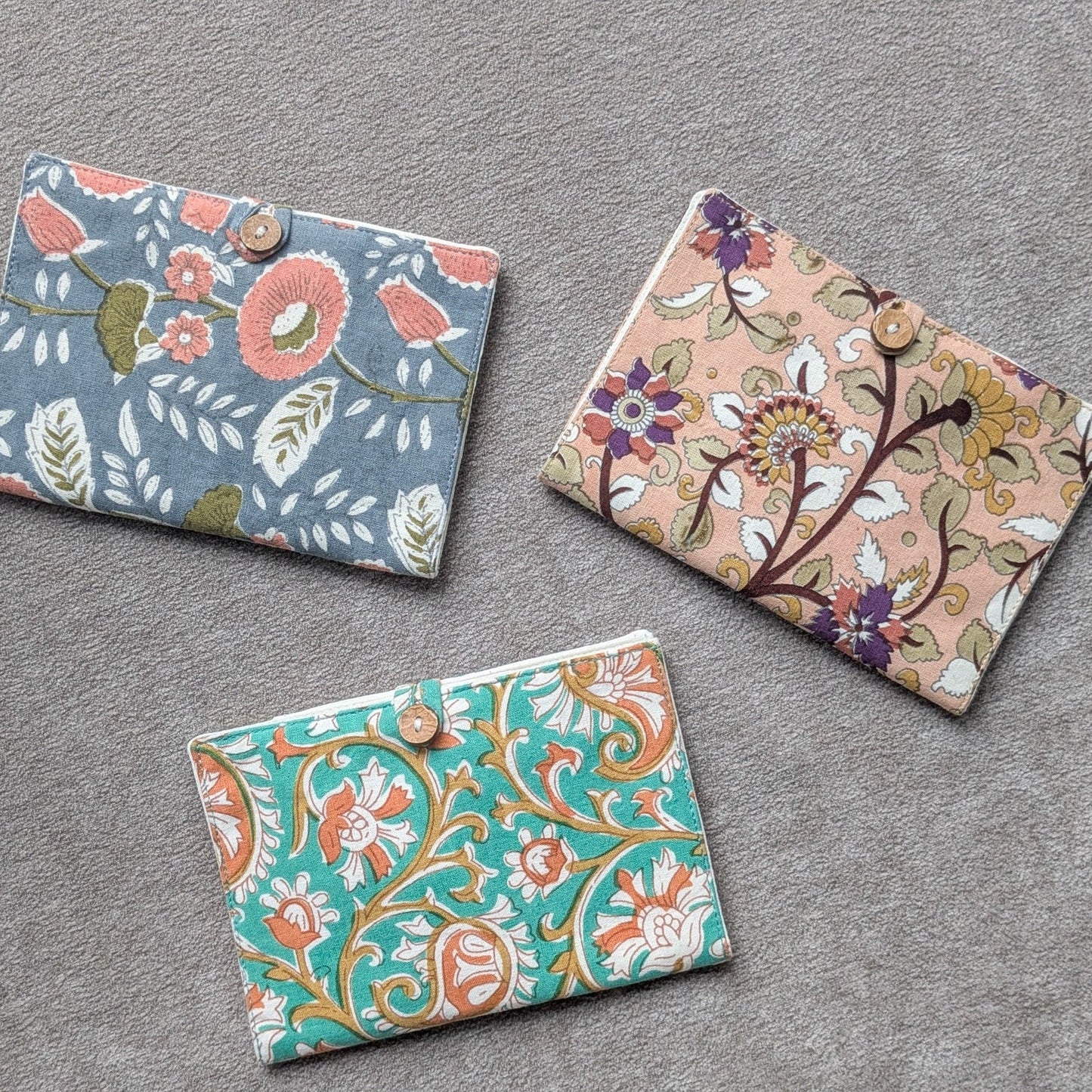 Three floral-patterned fabric passport covers on a gray surface