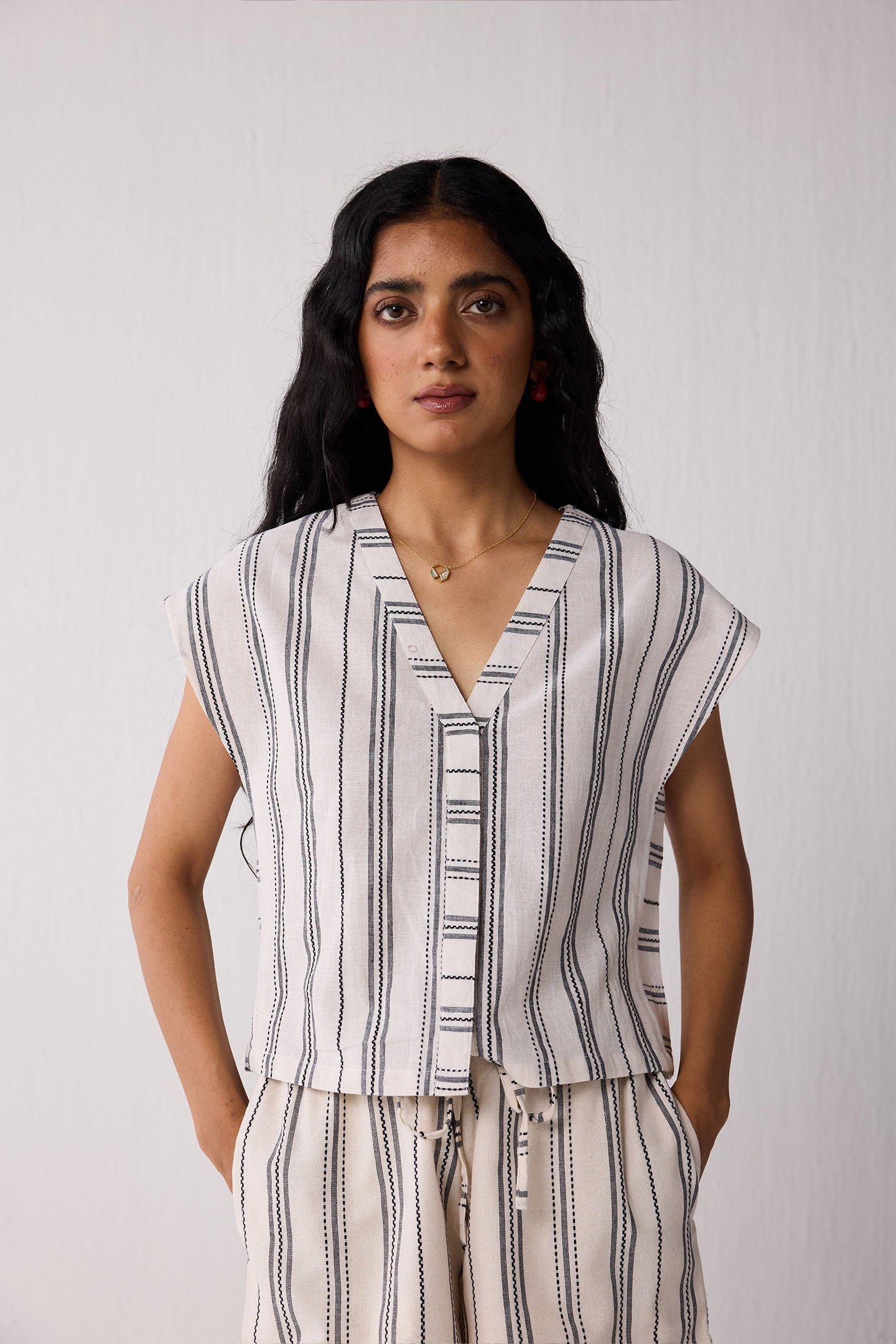 Woman wearing a striped top and shorts against a plain background