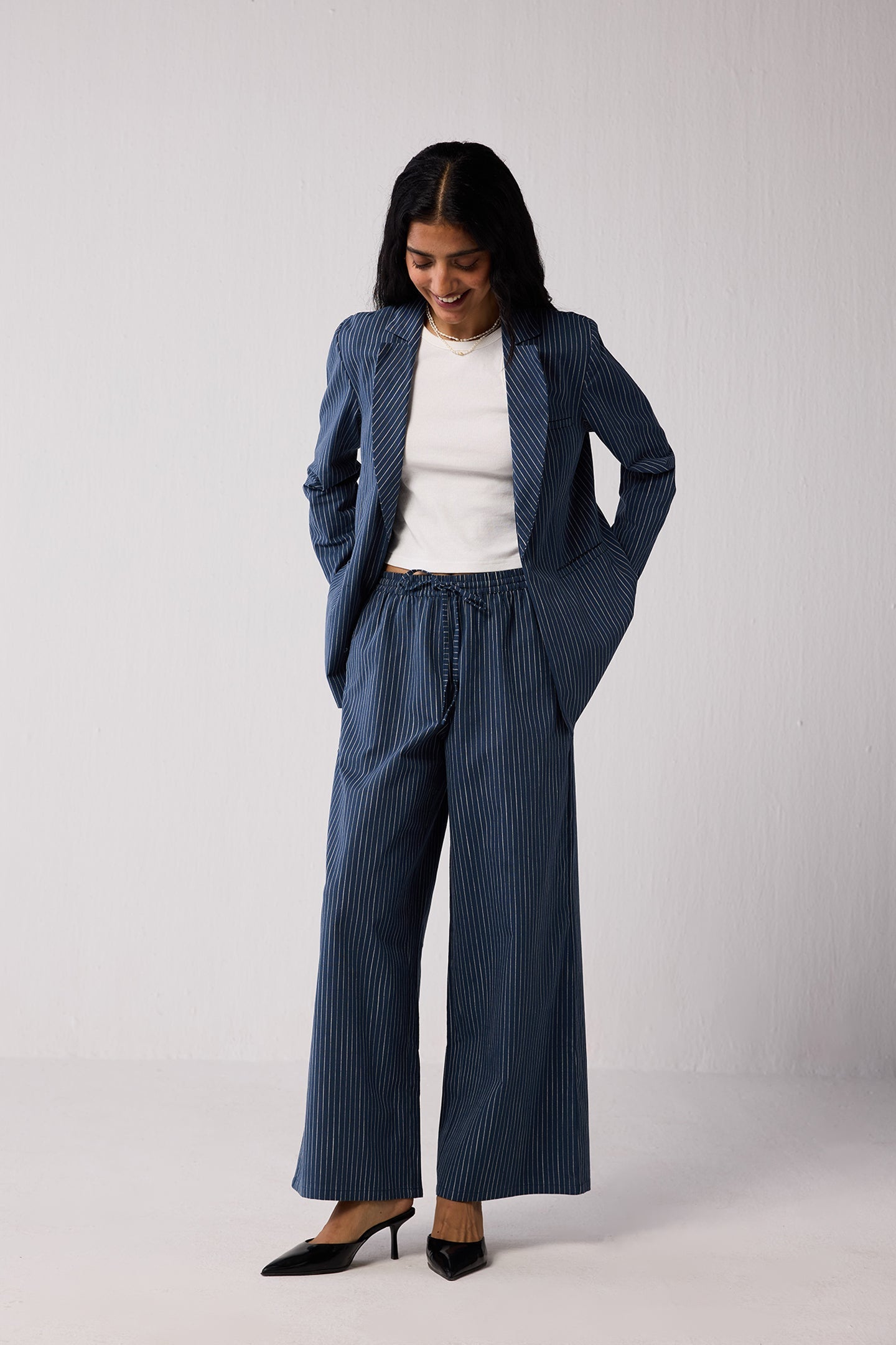 Woman wearing a blue pinstripe suit with a white top on a plain background