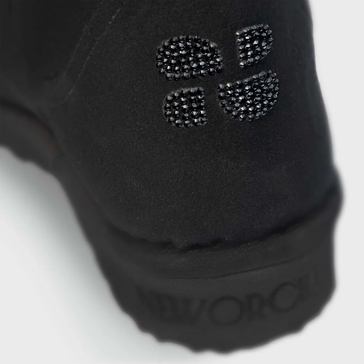 Close-up of a black vegan shoe with a brand logo on a white background