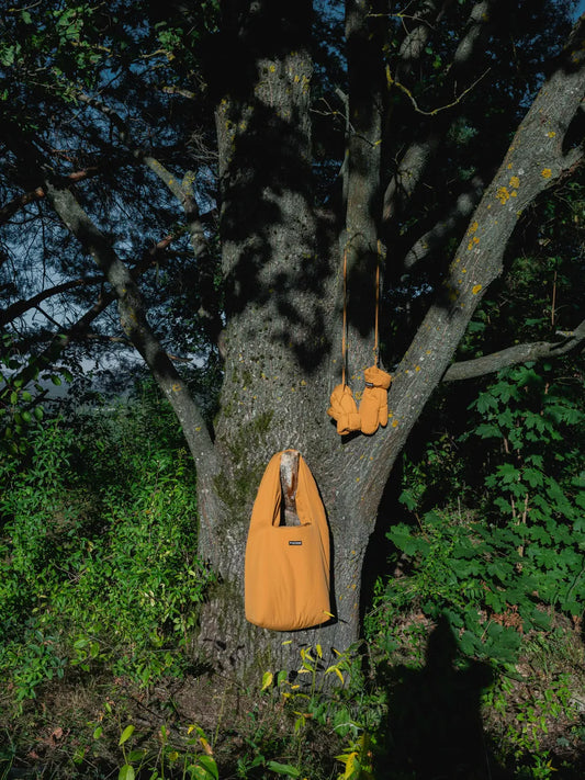 Amber yellow vegan winter gloves and matching tote bag made from recycled materials hanging on tree branch outdoors. - The New Orchard - Amber Yellow